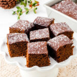 Closeup of squares of gingerbread on a cake plate.
