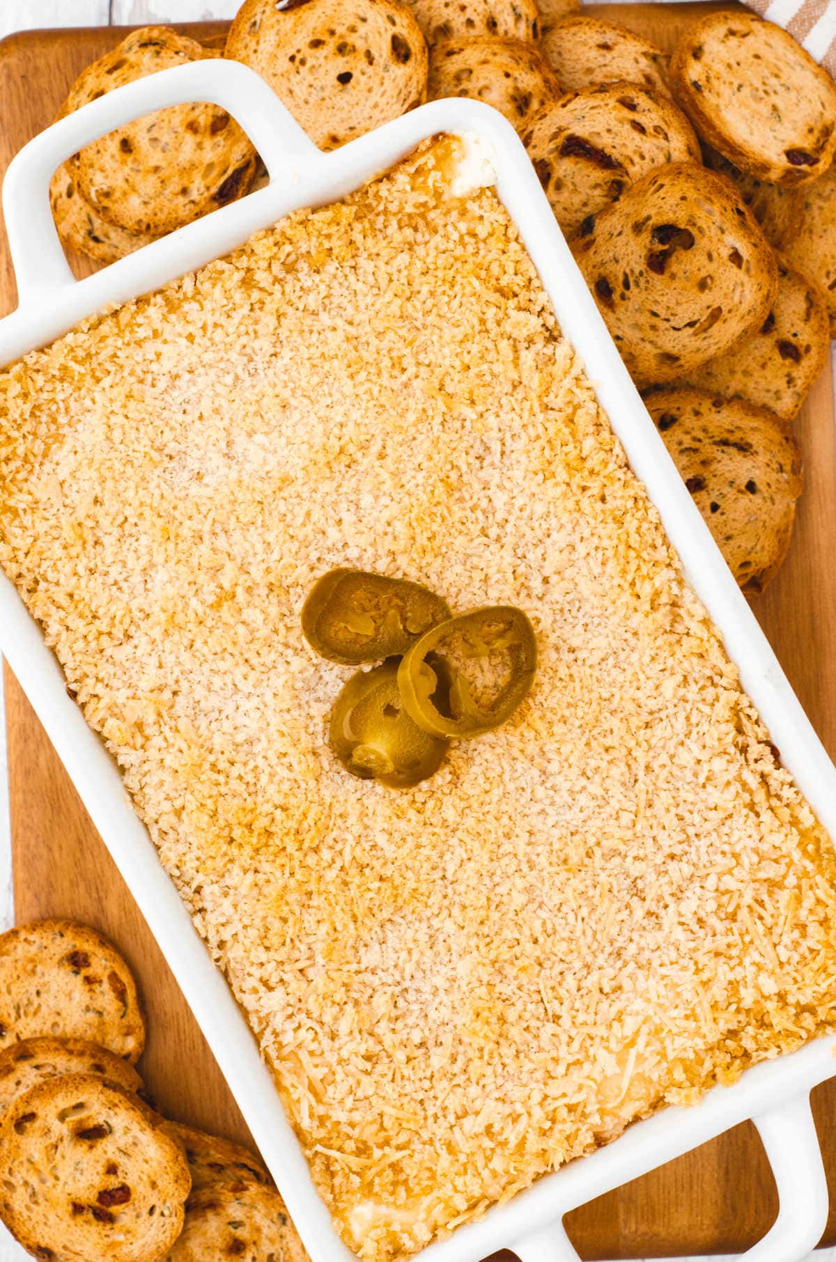 A finished pan of jalapeno cream cheese dip with crackers around it.