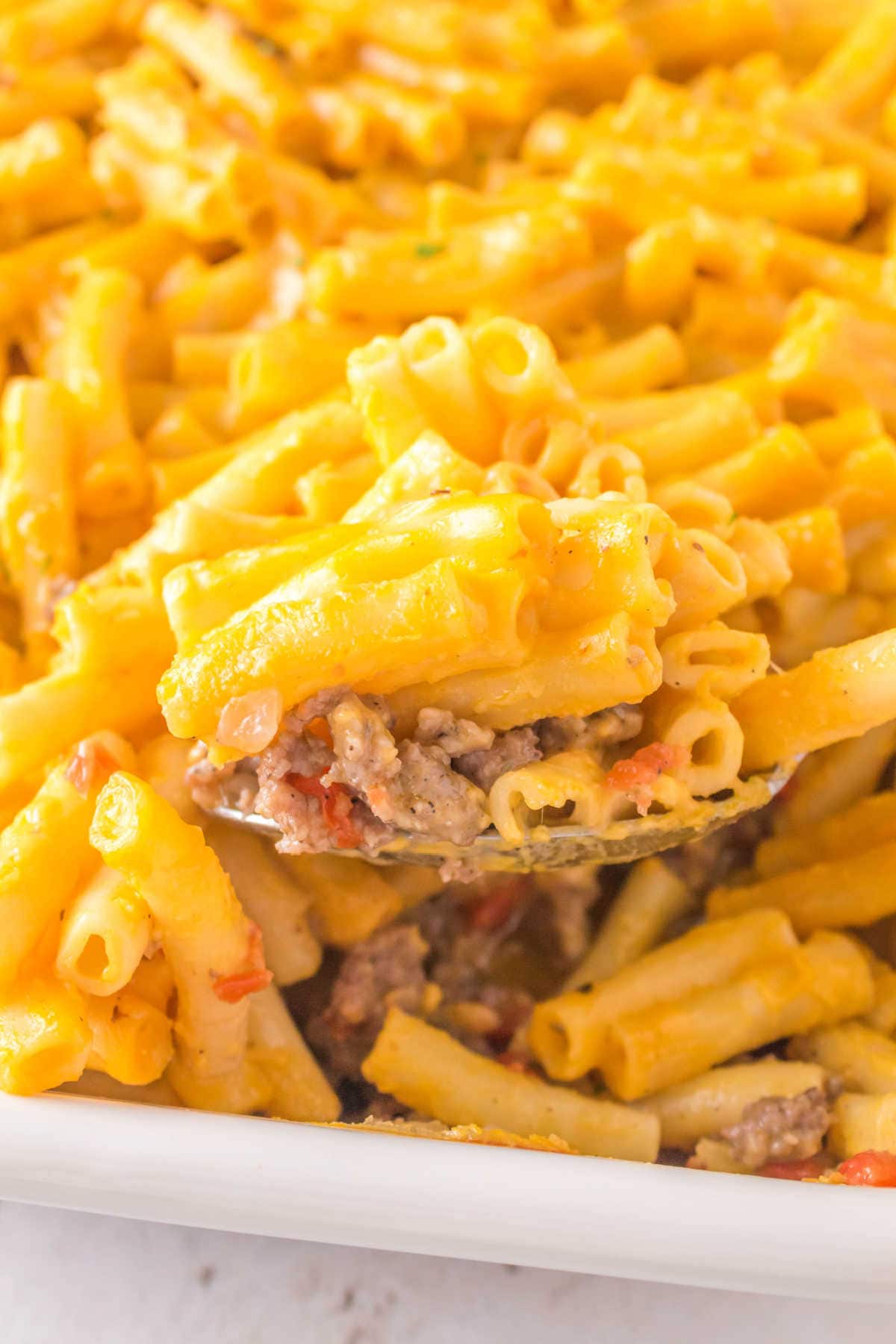 A serving of sausage and pasta being removed from the pan.