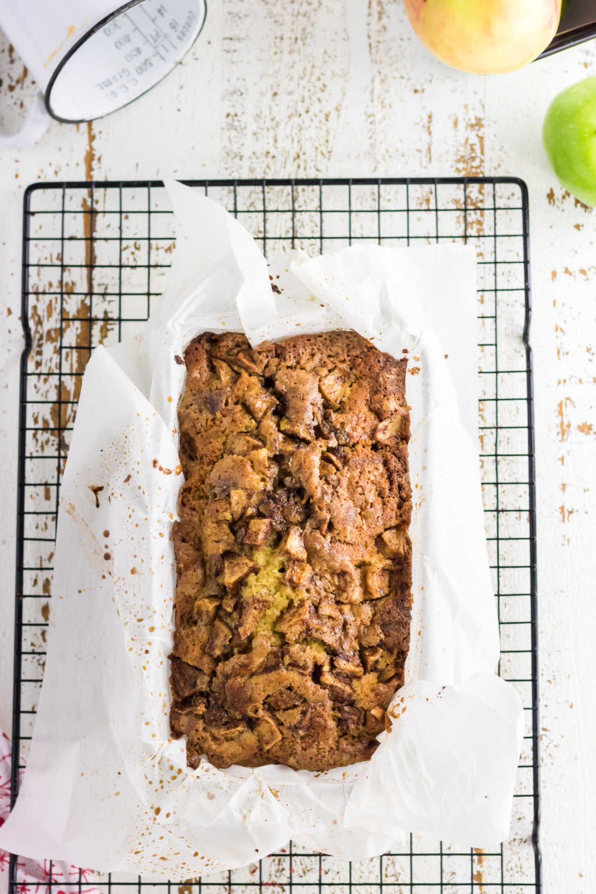 A loaf of apple bread cooling on a rack.