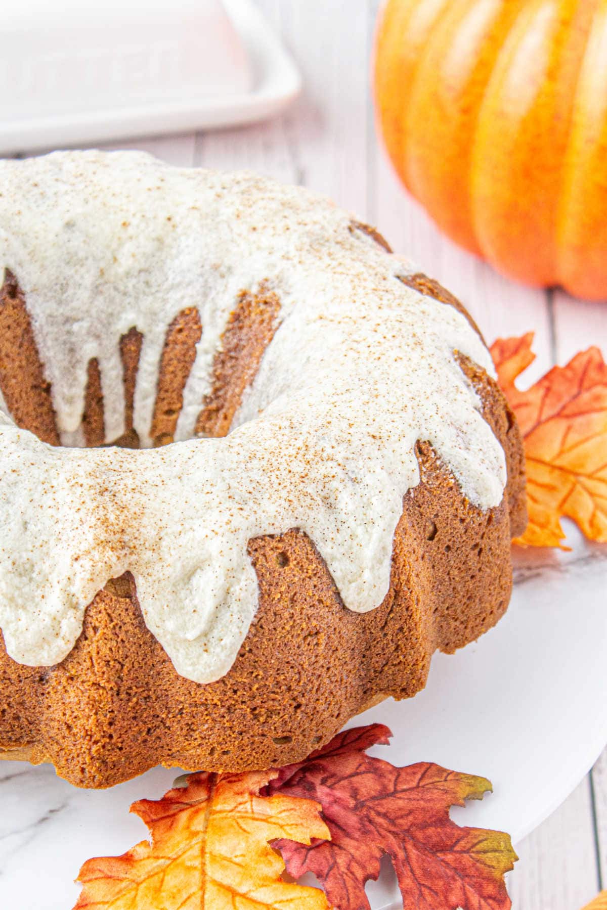 Pumpkin cake with glaze dripping down the sides.
