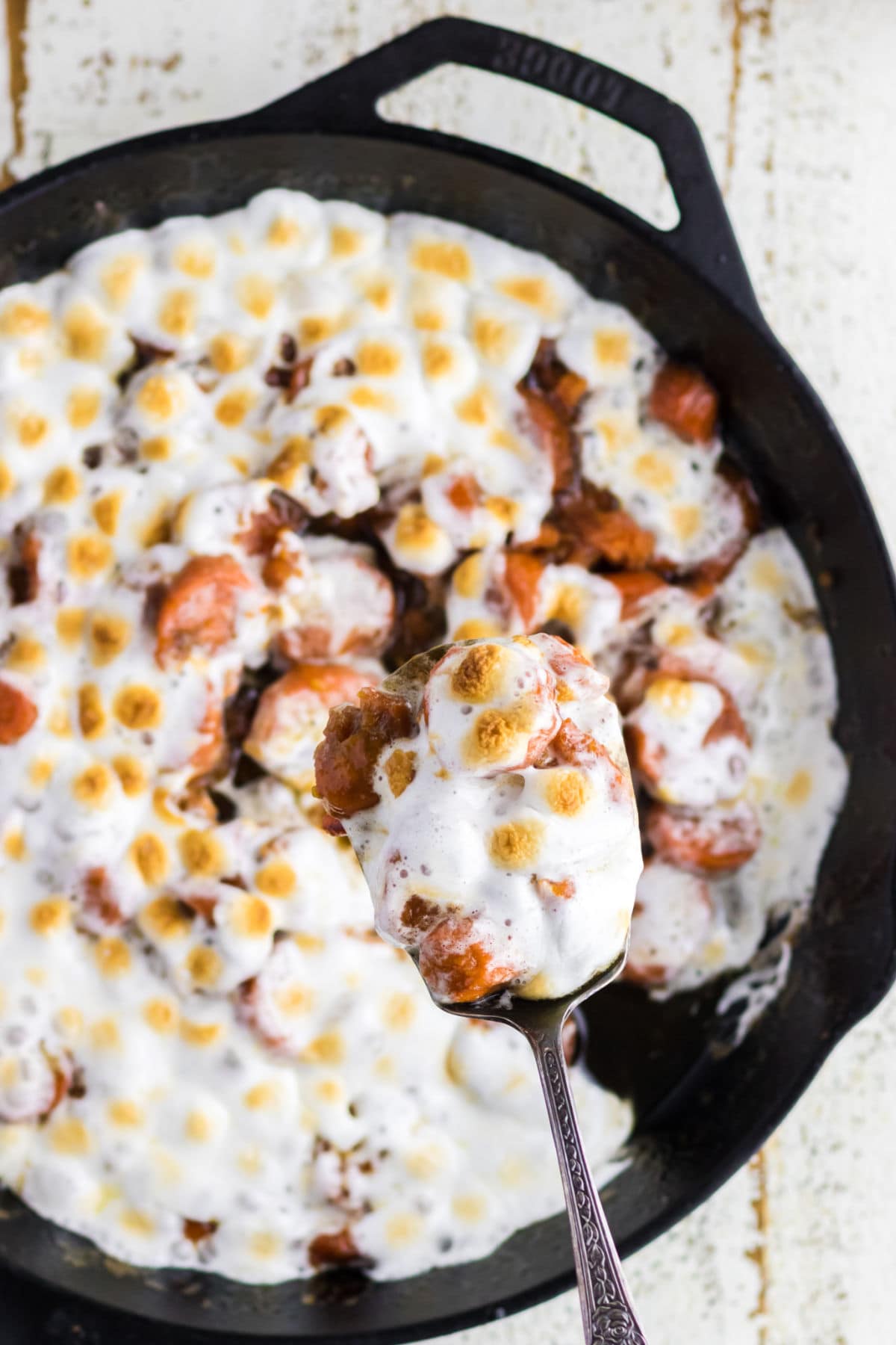 Serving of candied yams being removed from skillet.