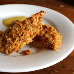 Closeup of crispy chicken tenders on a white plate.
