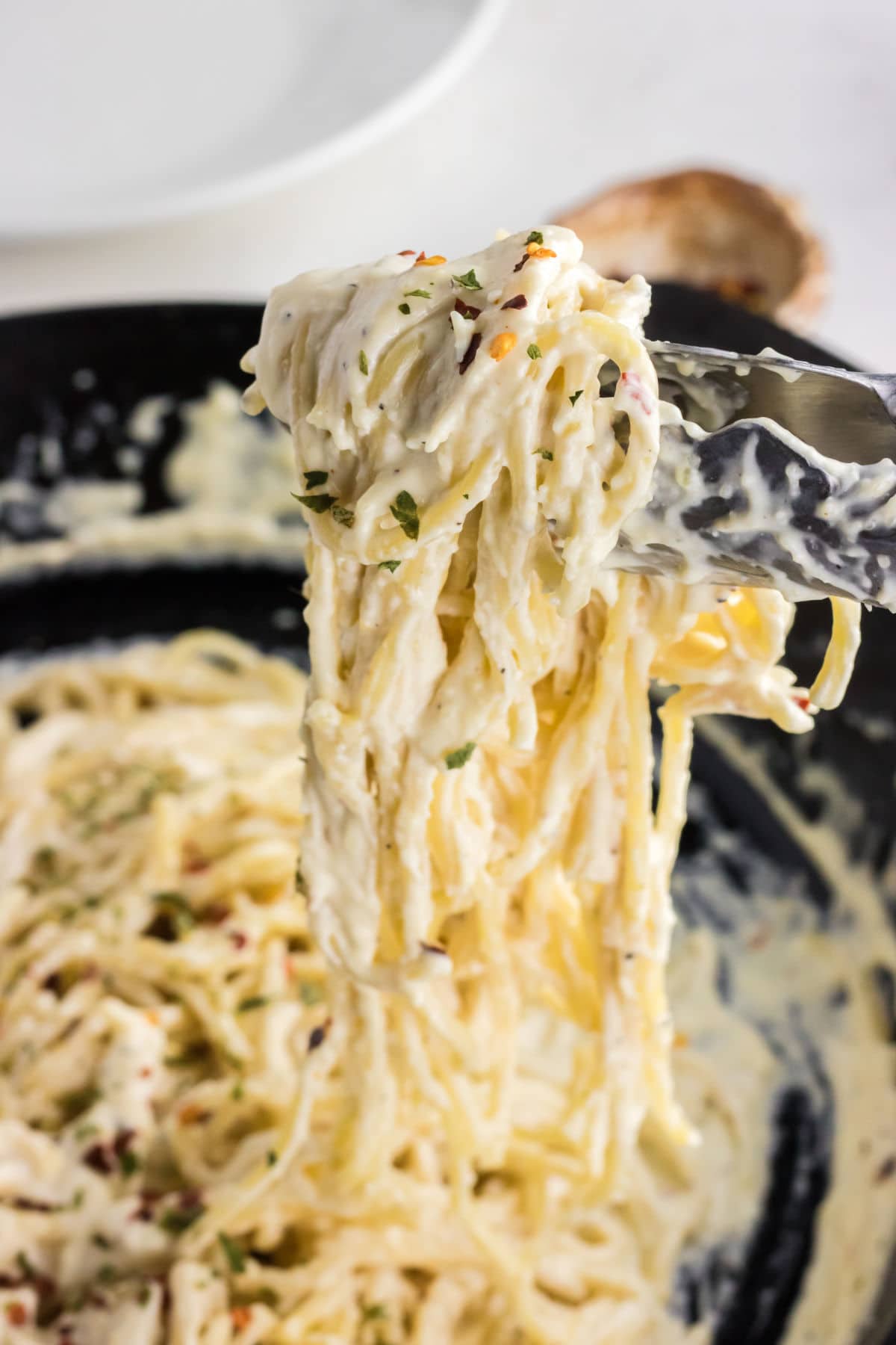 Cream cheese pasta on tongs.