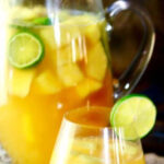 Closeup of a glass of sangria with a pitcher in the background. Image has a text overlay for Pinterest.