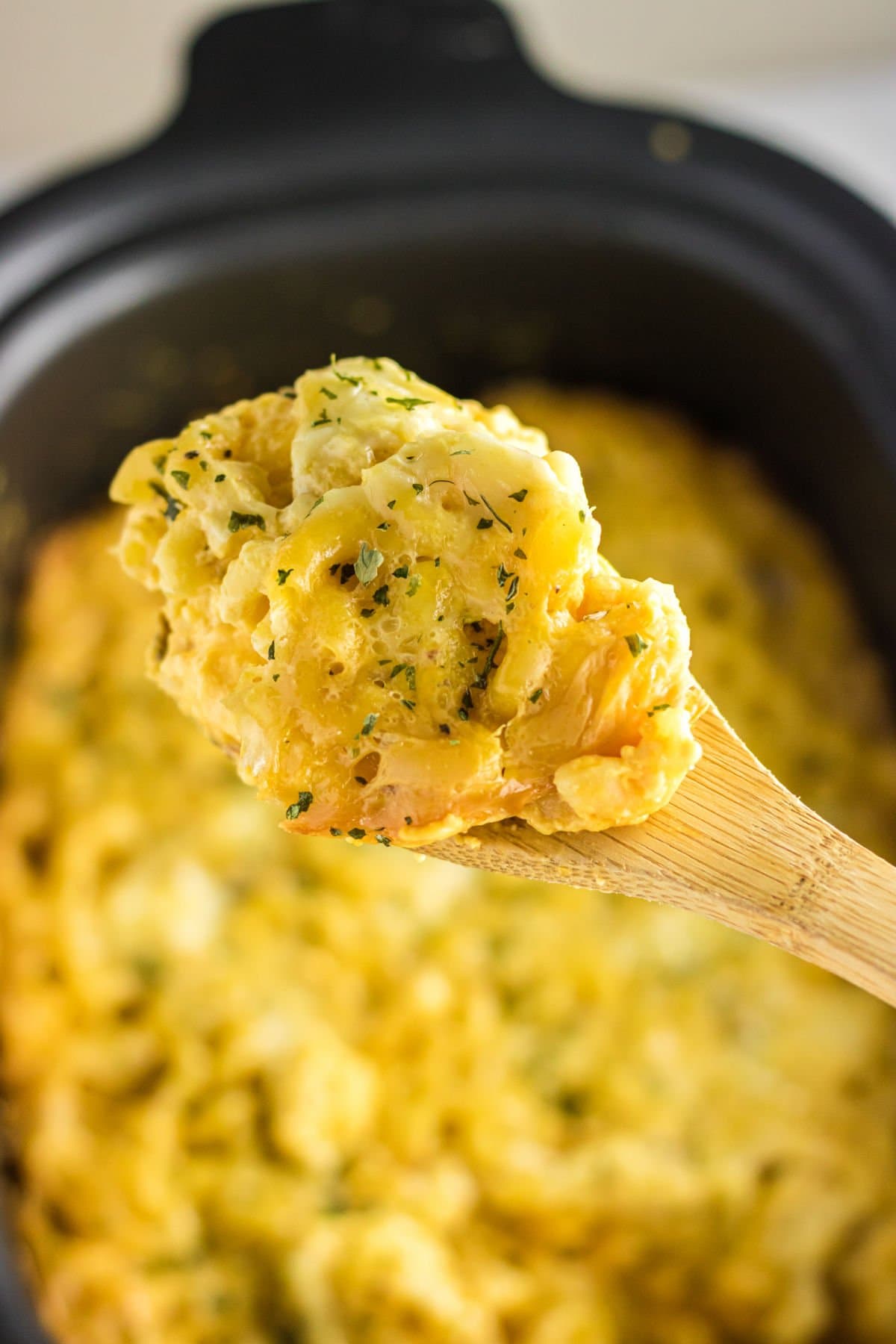 A spoonful of mac & cheese being removed from the slow cooker.