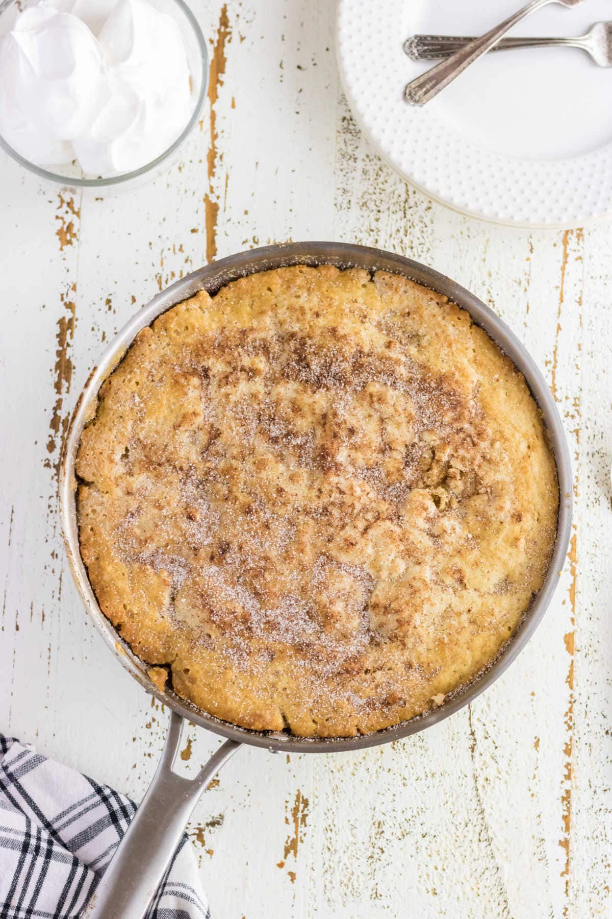 Overhead view of finished peach cobbler in a skillet.