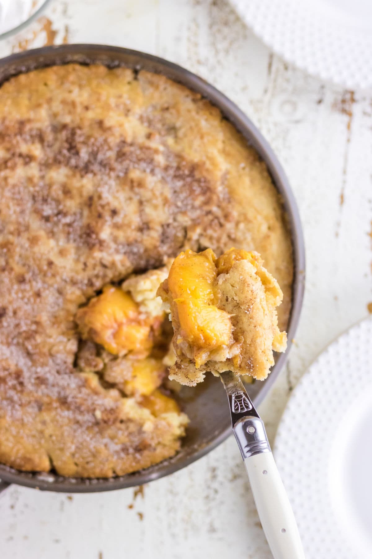 A scoop of peach cobbler being removed from a pan.