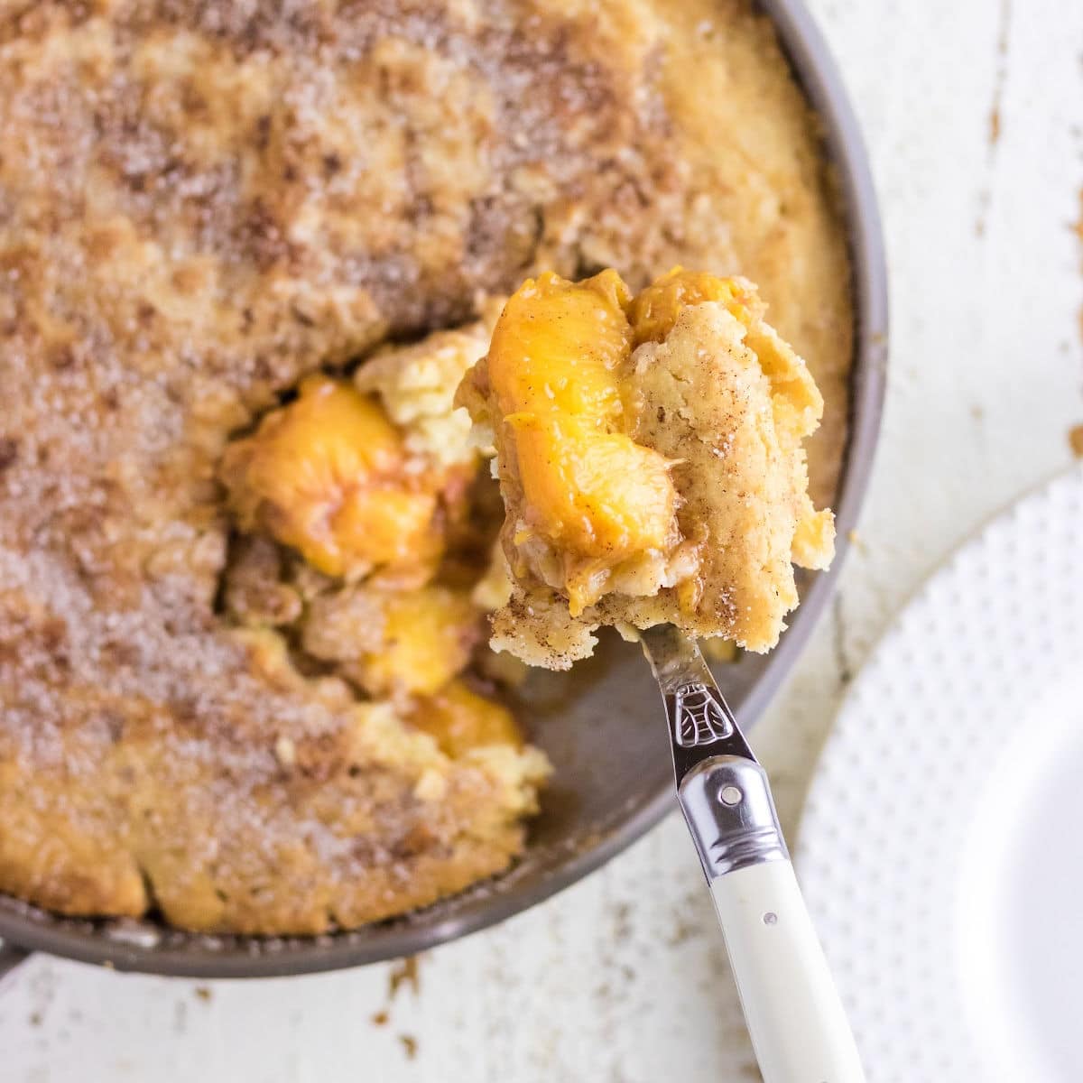 Feature image; a serving of cobbler being removed from the skillet.