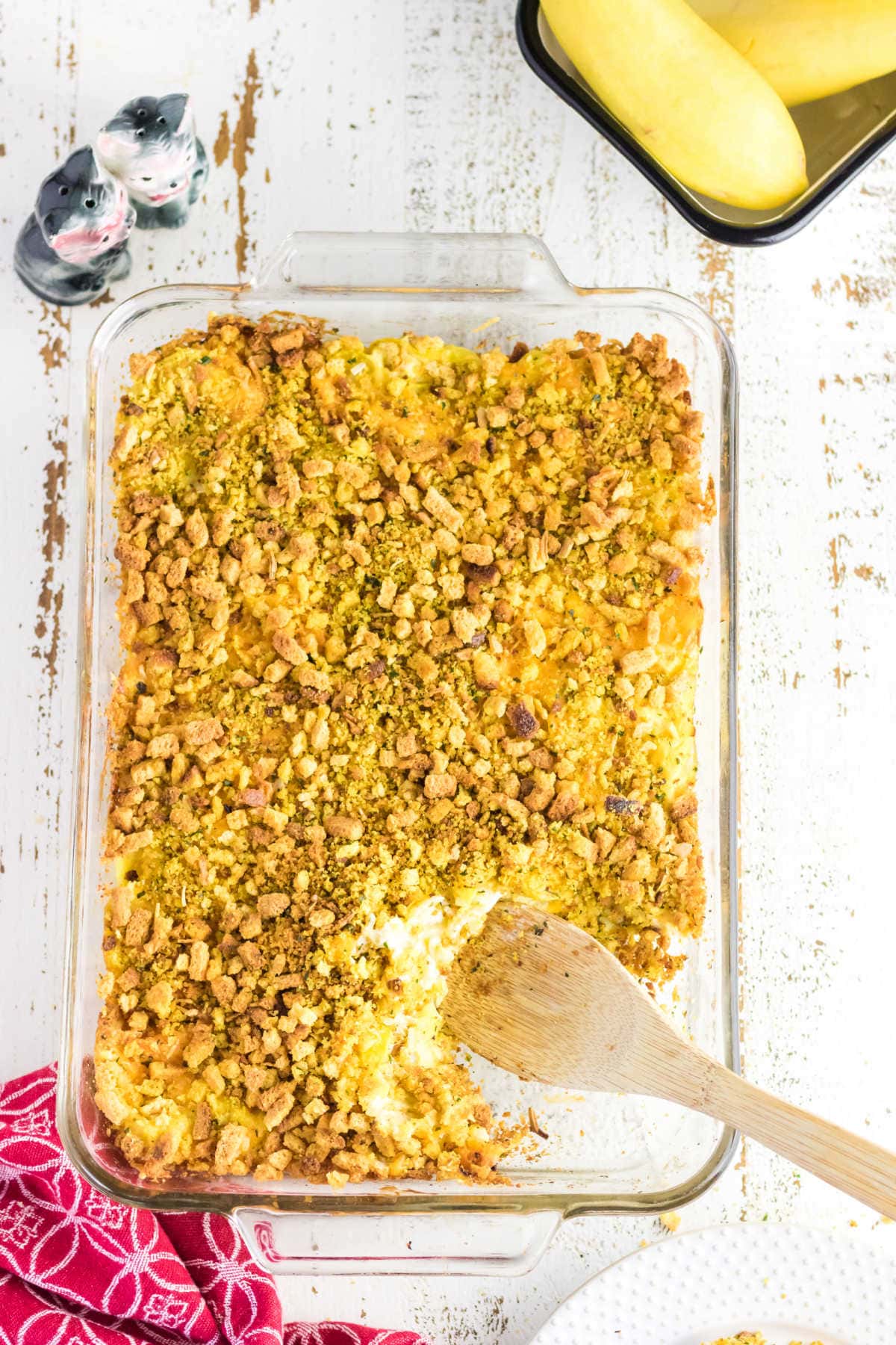 Overhead view of casserole with a wooden spoon removing a serving