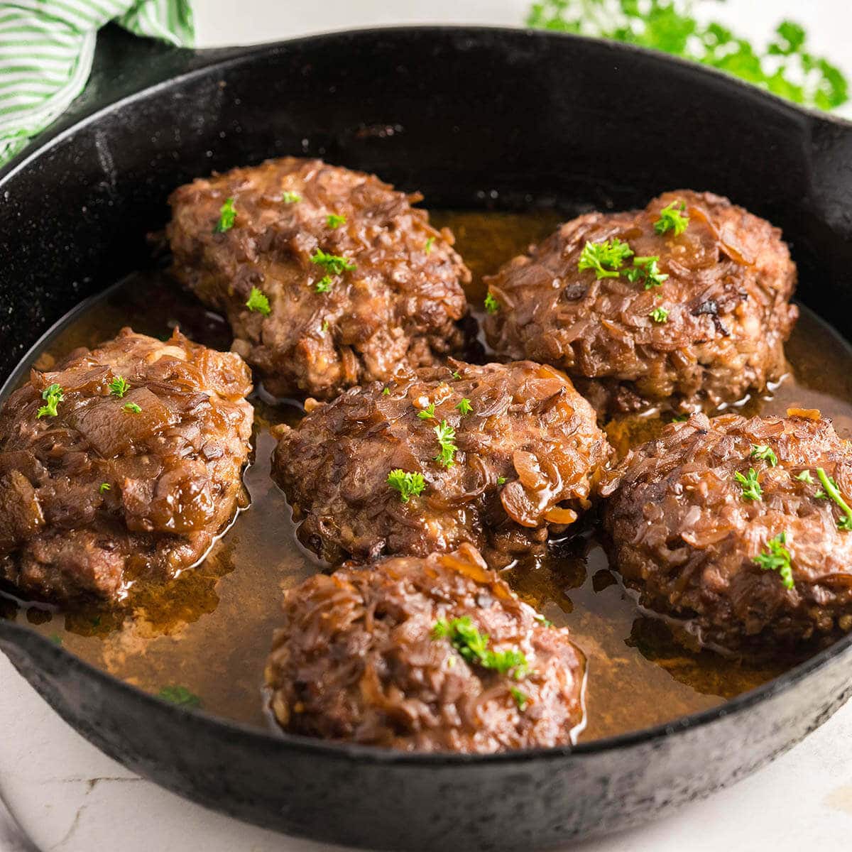 Salisbury steaks and gravy in a skillet.