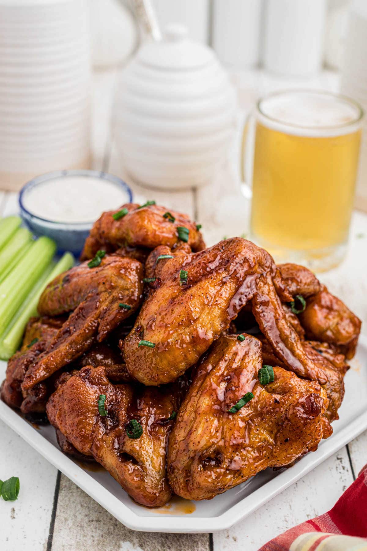 A platter of wings on a table with a glass of beer.