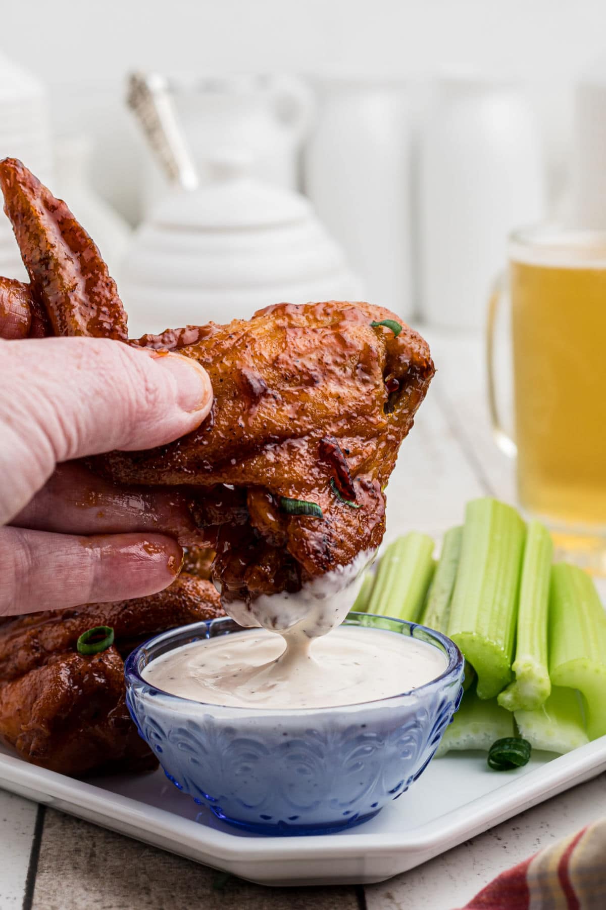 Someone dipping wings into Ranch dressing.