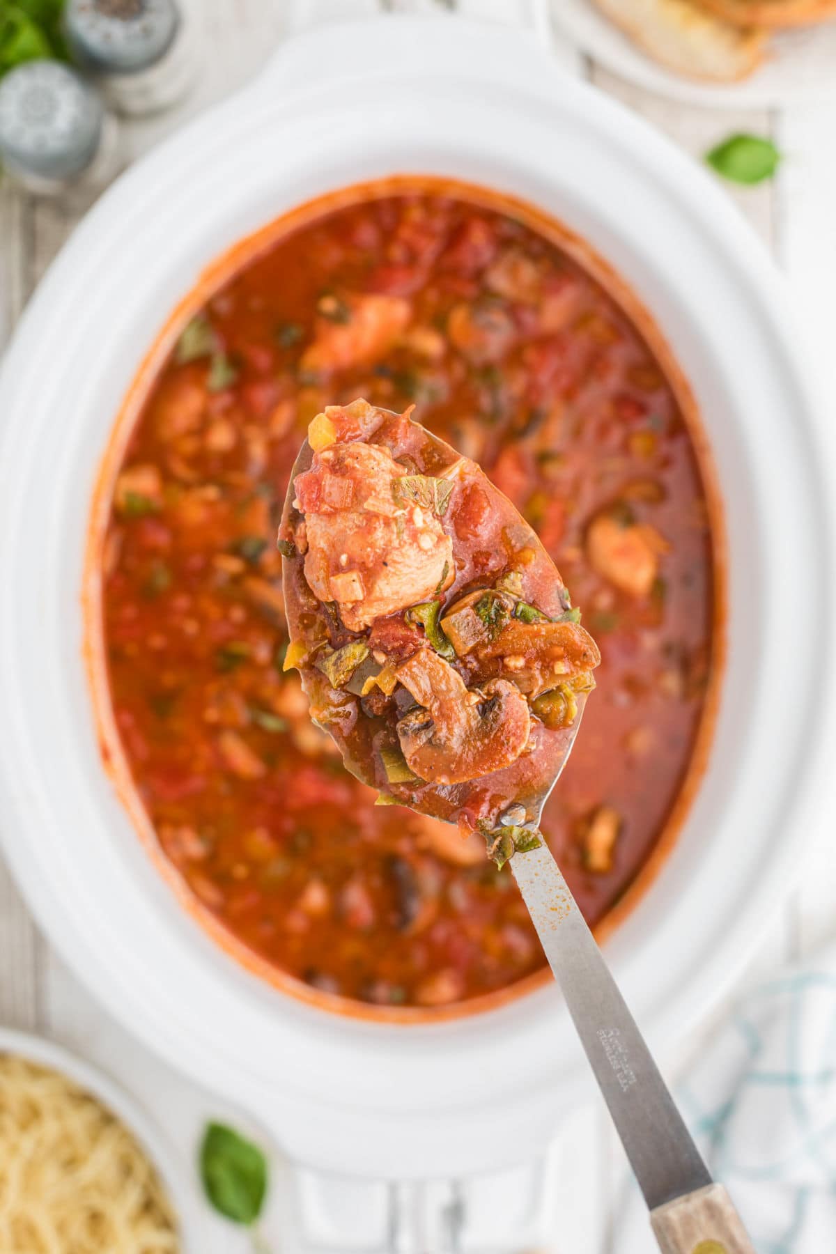 A spoonful of chicken cacciatore being removed from the slow cooker.