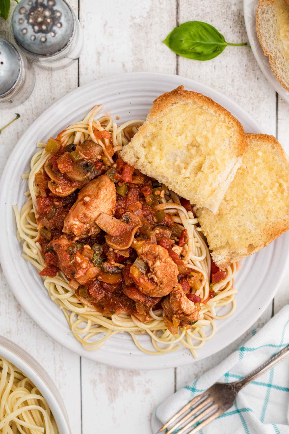 Overhead view of chicken cacciatore on a plate with garlic bread.