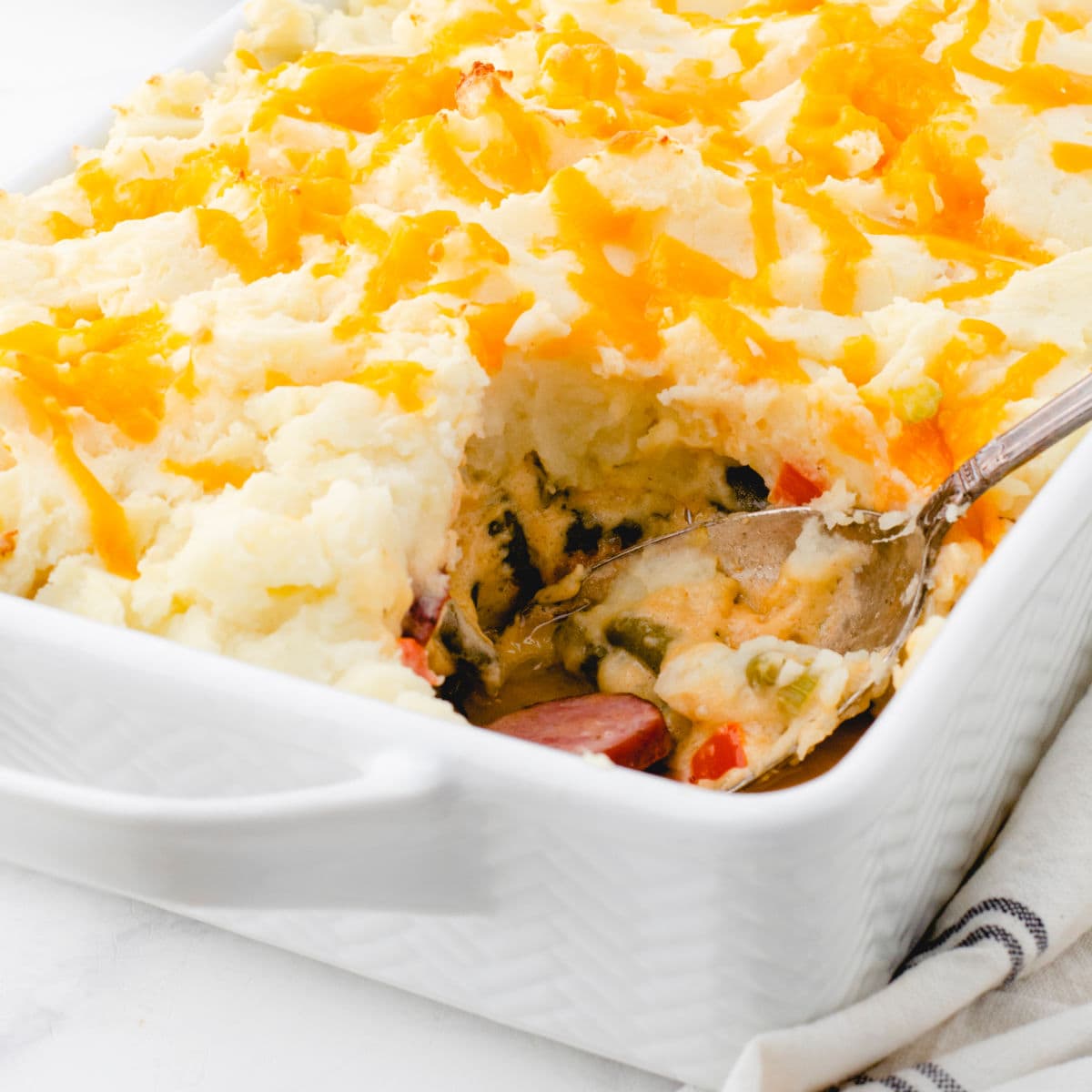 Closeup of smoked sausage shepherd's pie with a serving removed.