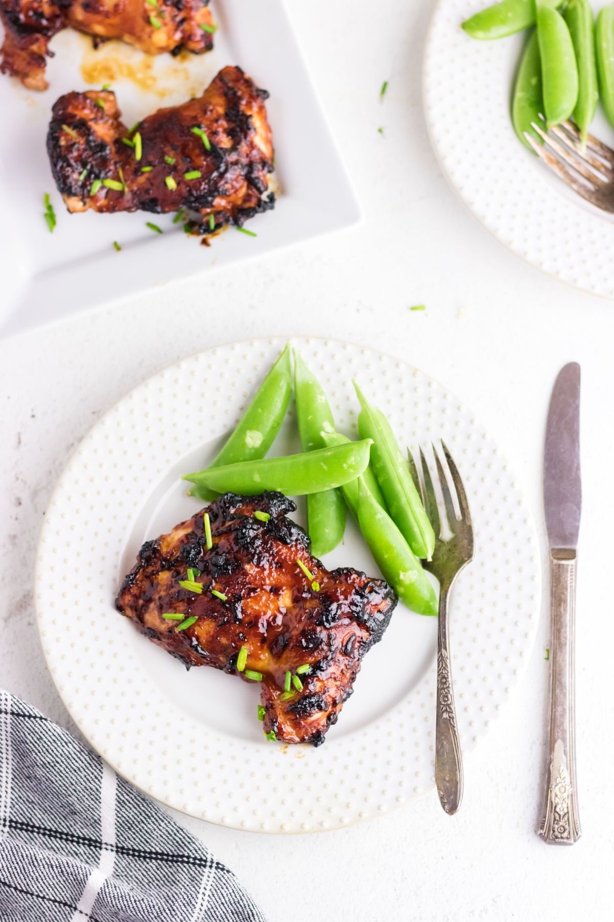 Overhead view of finished bbq chicken thighs on a white plate.