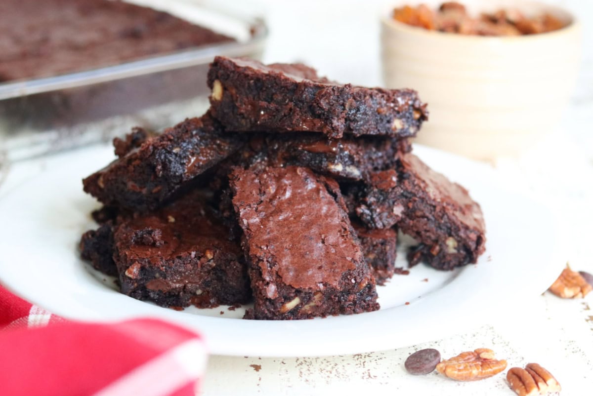 A white plate with brownies stacked on it.
