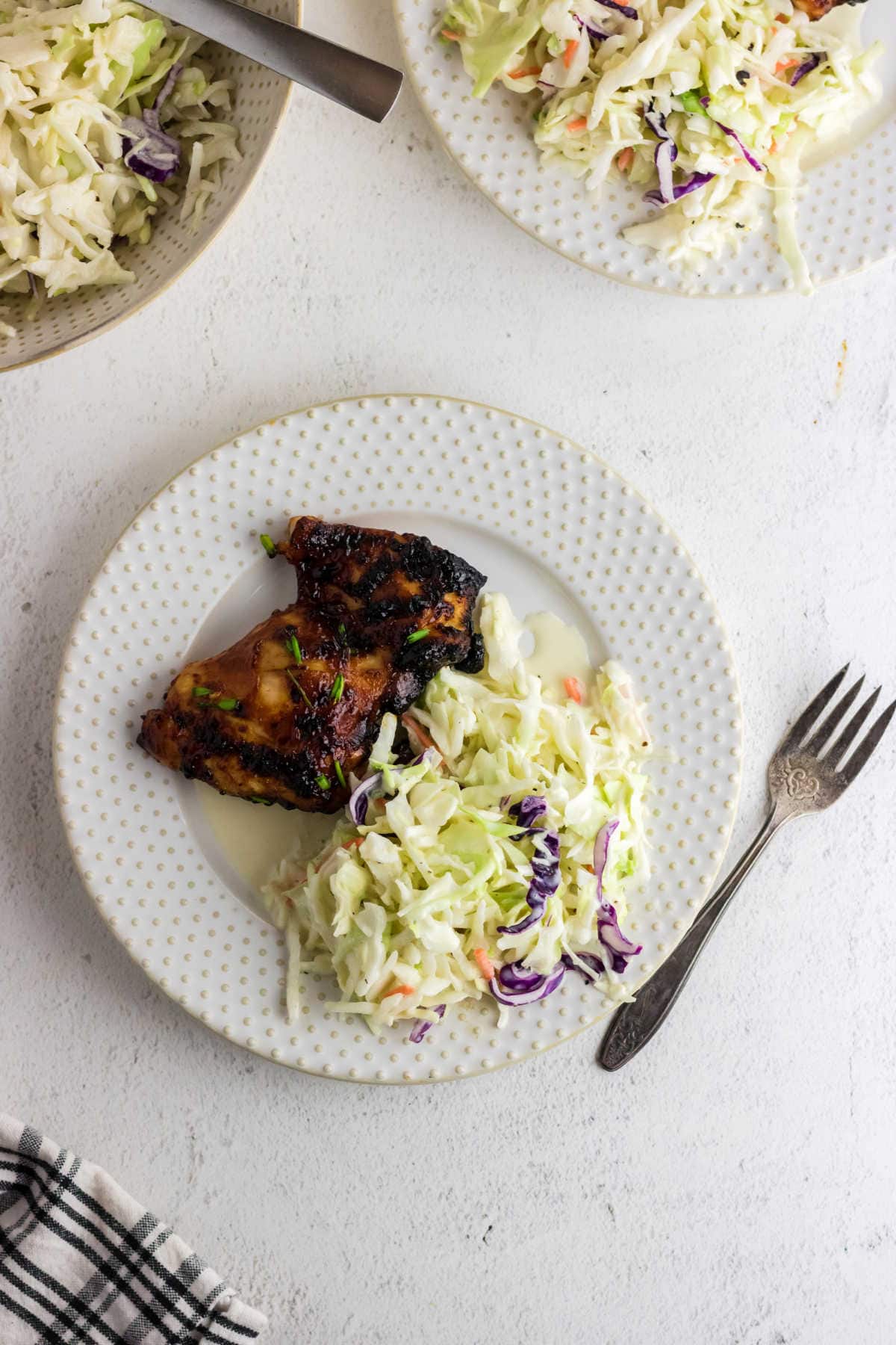 Coleslaw on a plate with bbq chicken.