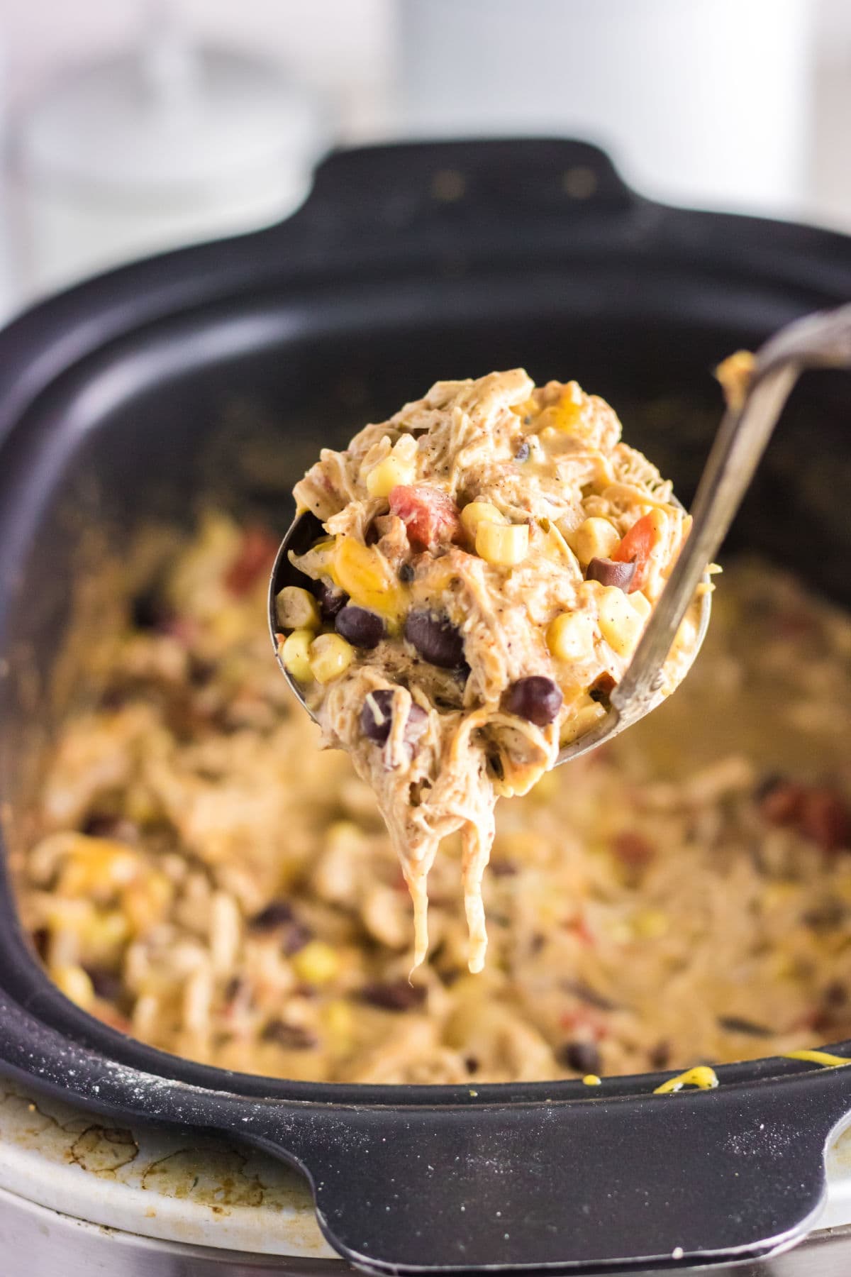 A ladleful of chicken chili being removed from the slow cooker.