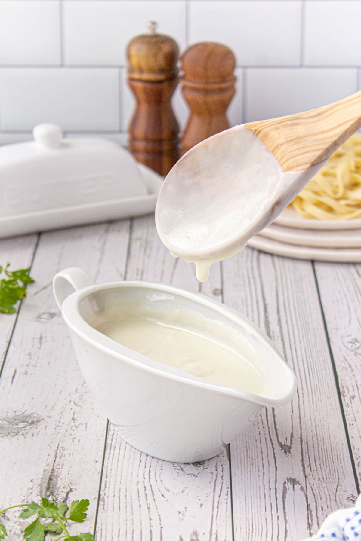 A white gravy boat with cream sauce in it.