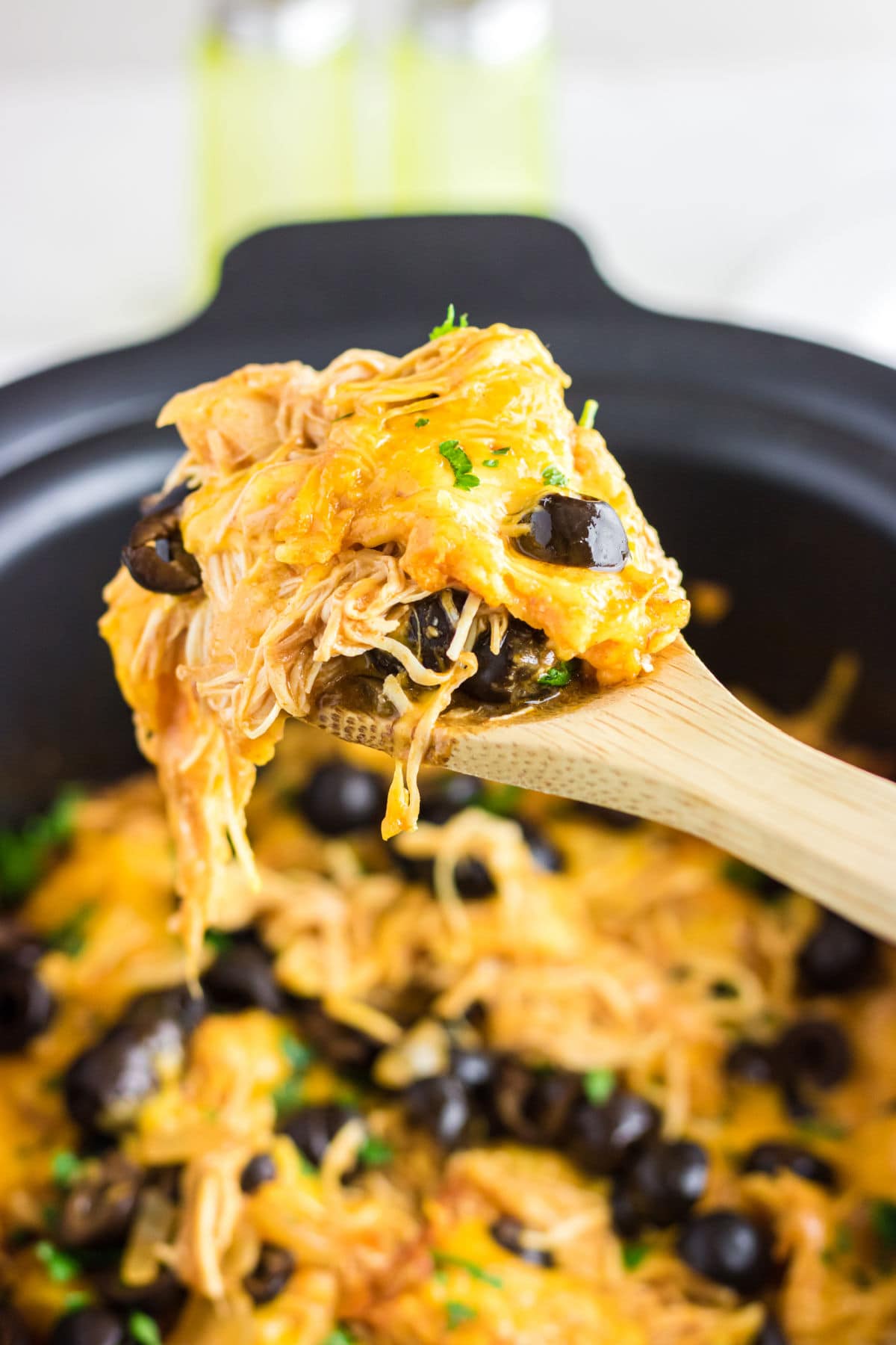 A spoonful of enchilada casserole being removed from the slow cooker.