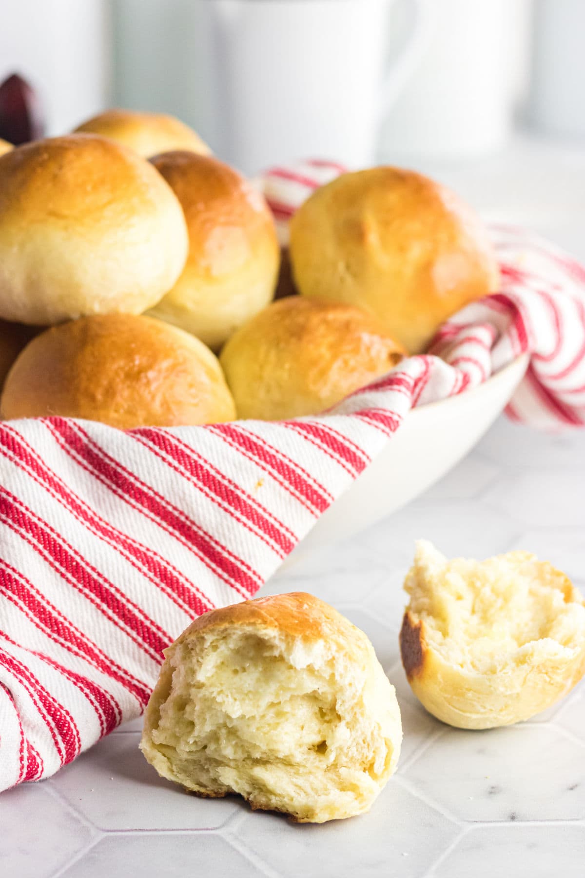 A basket of dinner rolls with one opened to show the soft interior.