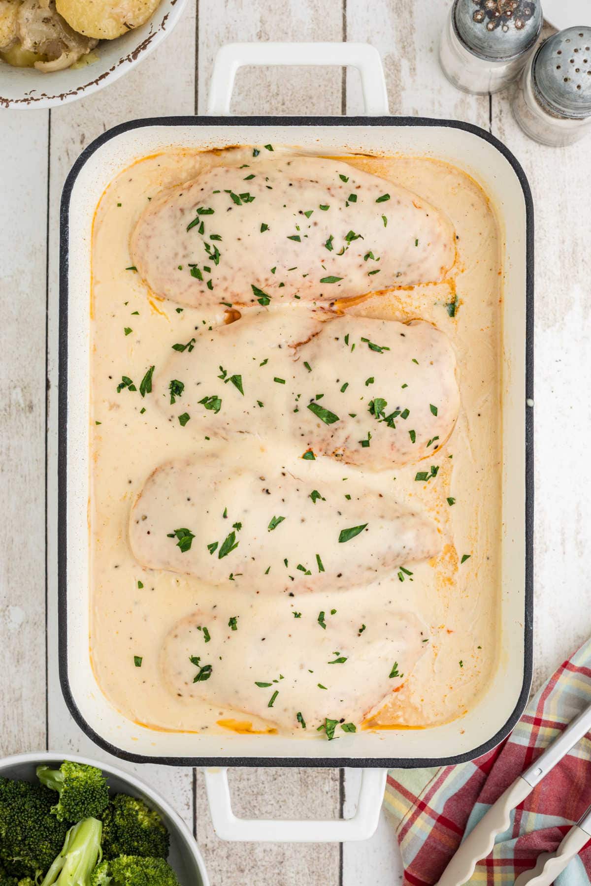 Overhead view of the chicken covered in gravy in a white casserole dish.