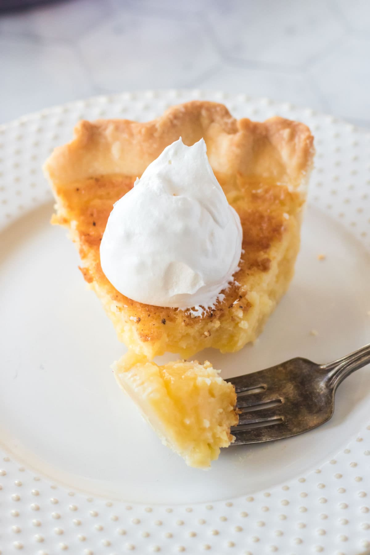 A slice of buttermilk pie with a piece on a fork.