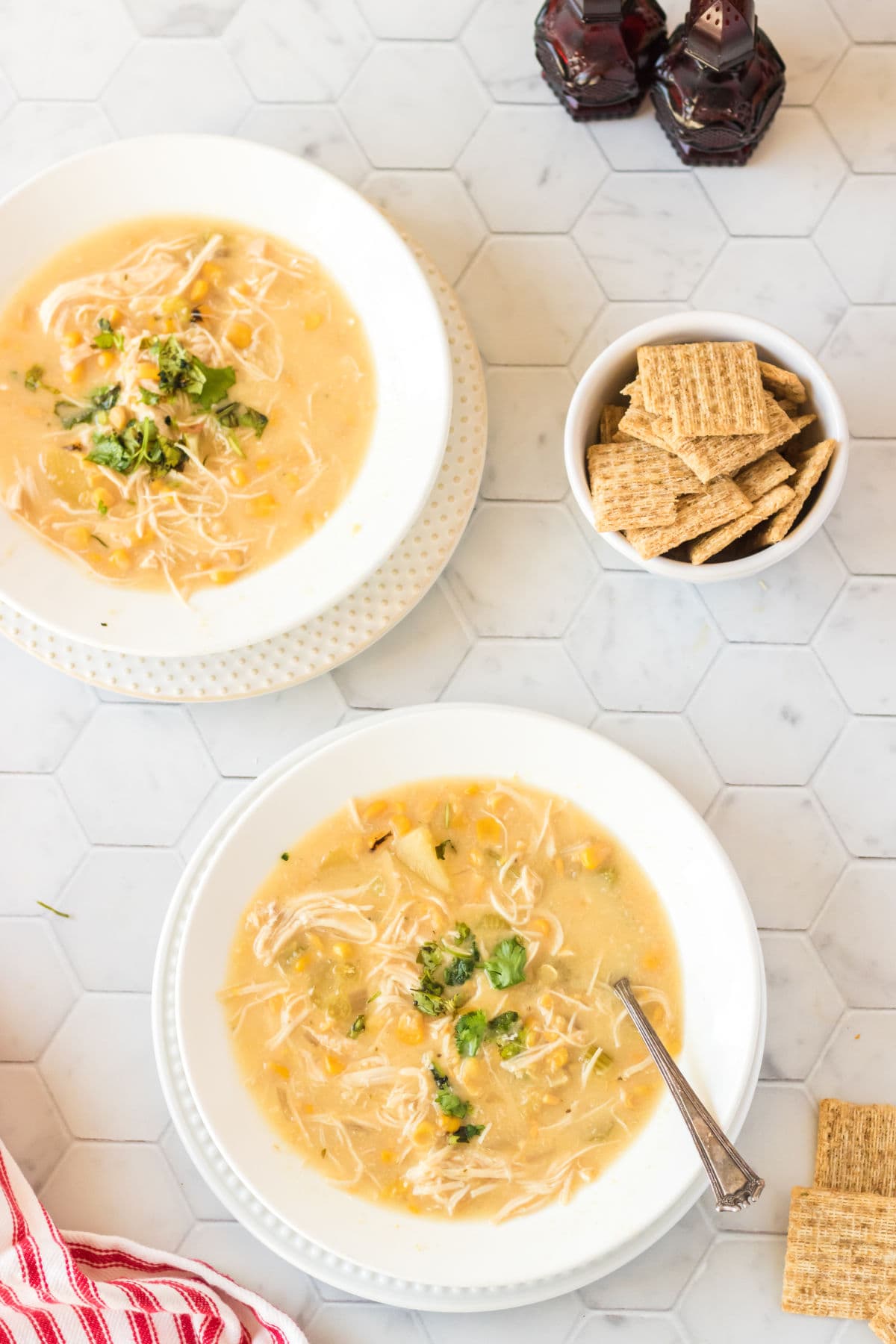 Chicken corn chowder in white bowl with a spoon and crackers.