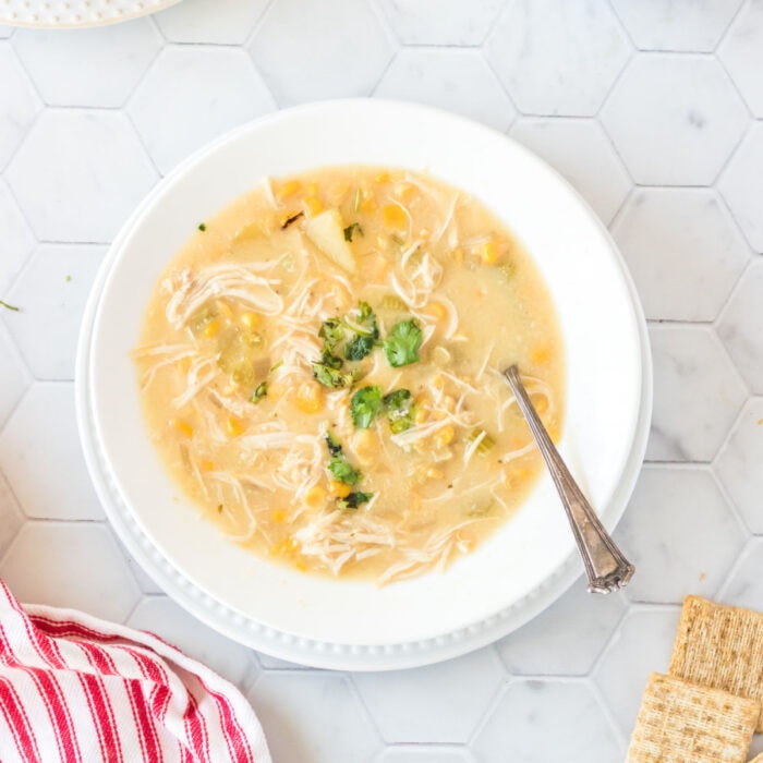 Crockpot chicken corn chowder with a spoon in it.