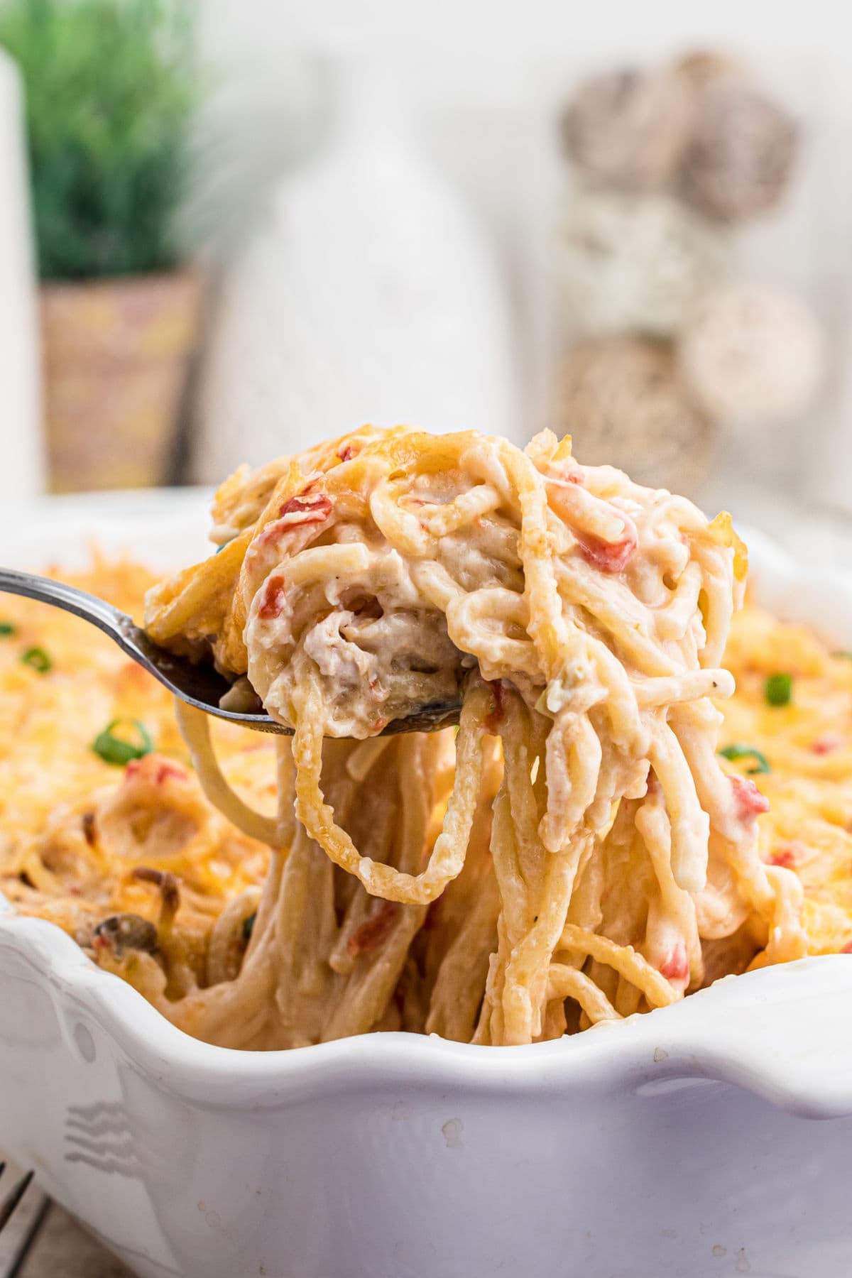 A serving of chicken spaghetti with a thick creamy sauce being removed from the dish.