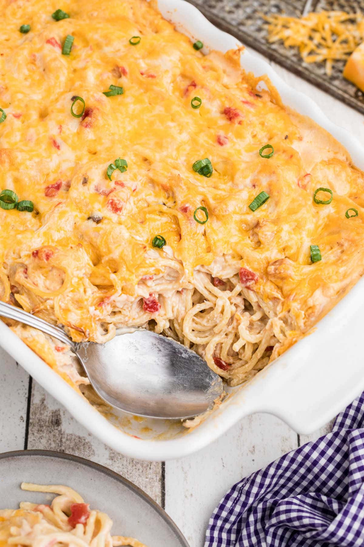 Close up of a casserole dish of chicken spaghetti with a serving removed.