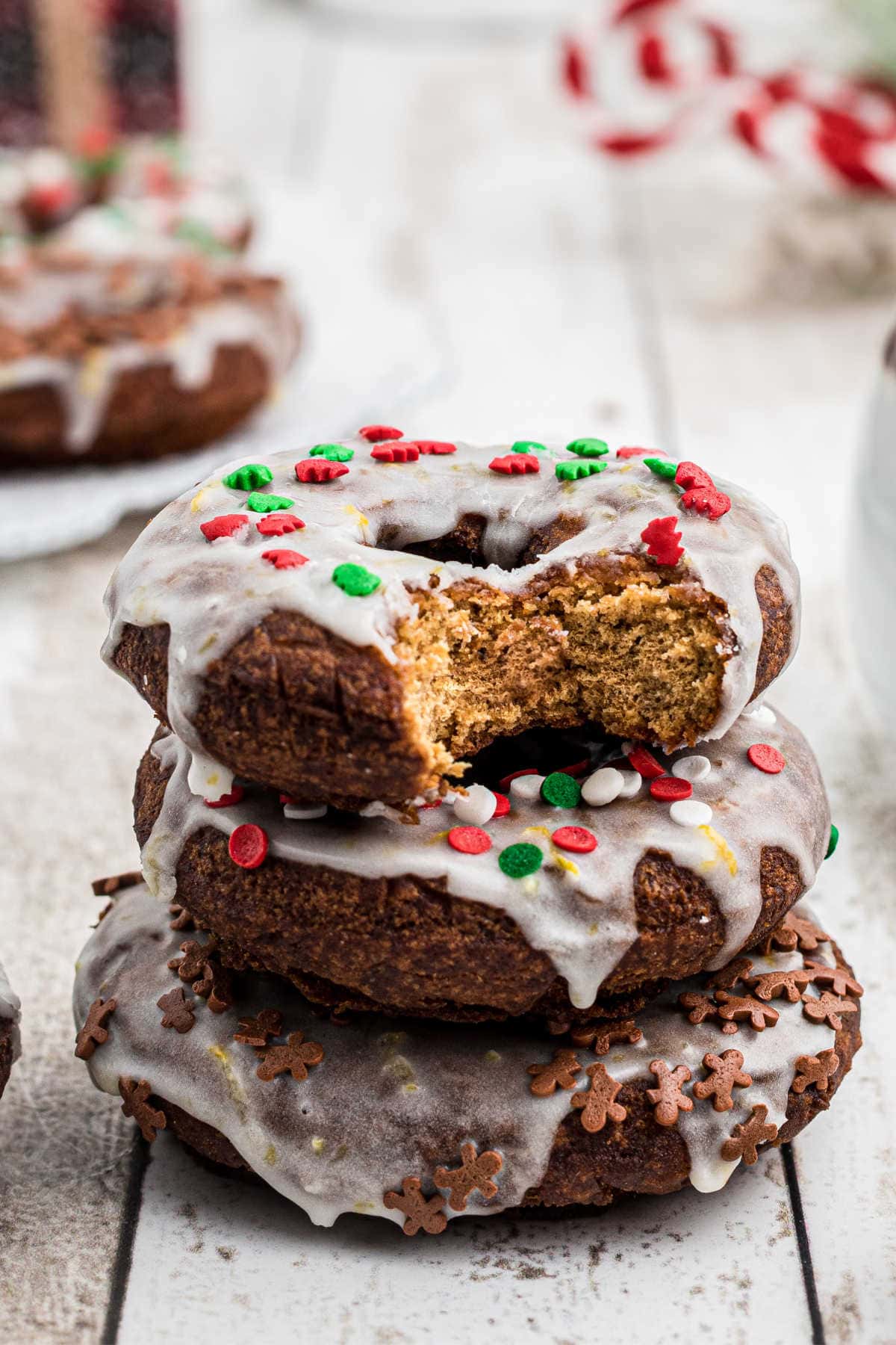 Three gingerbread donuts stacked on top of each other with a bite taken out of one.