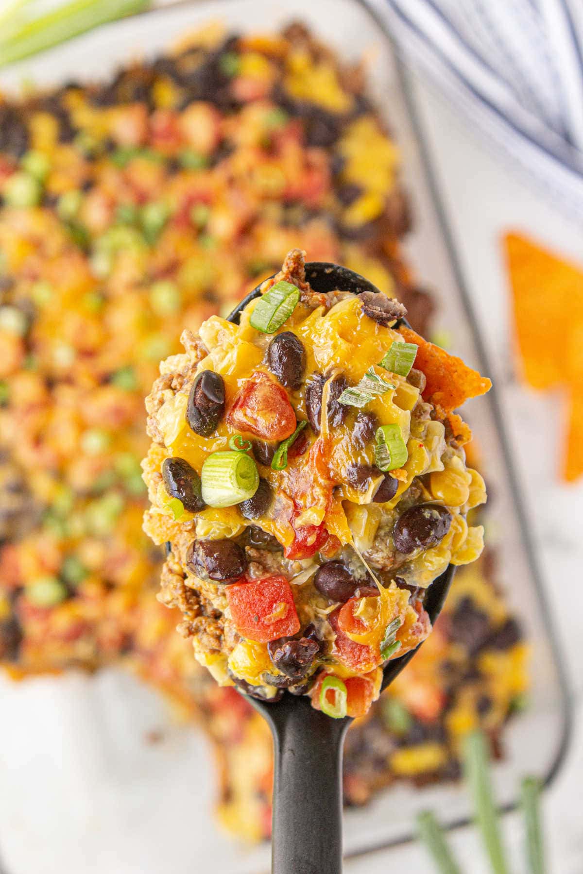 Overhead shot of spoon with ground beef Dorito casserole.