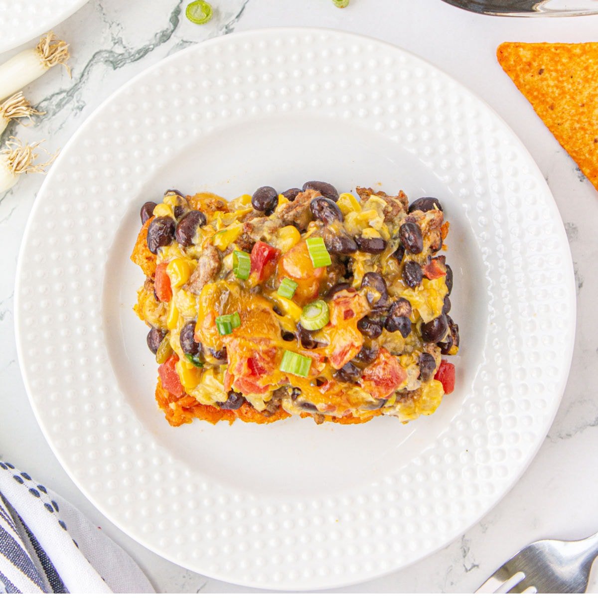 Serving of Ground Beef Dorito Casserole on white plate.