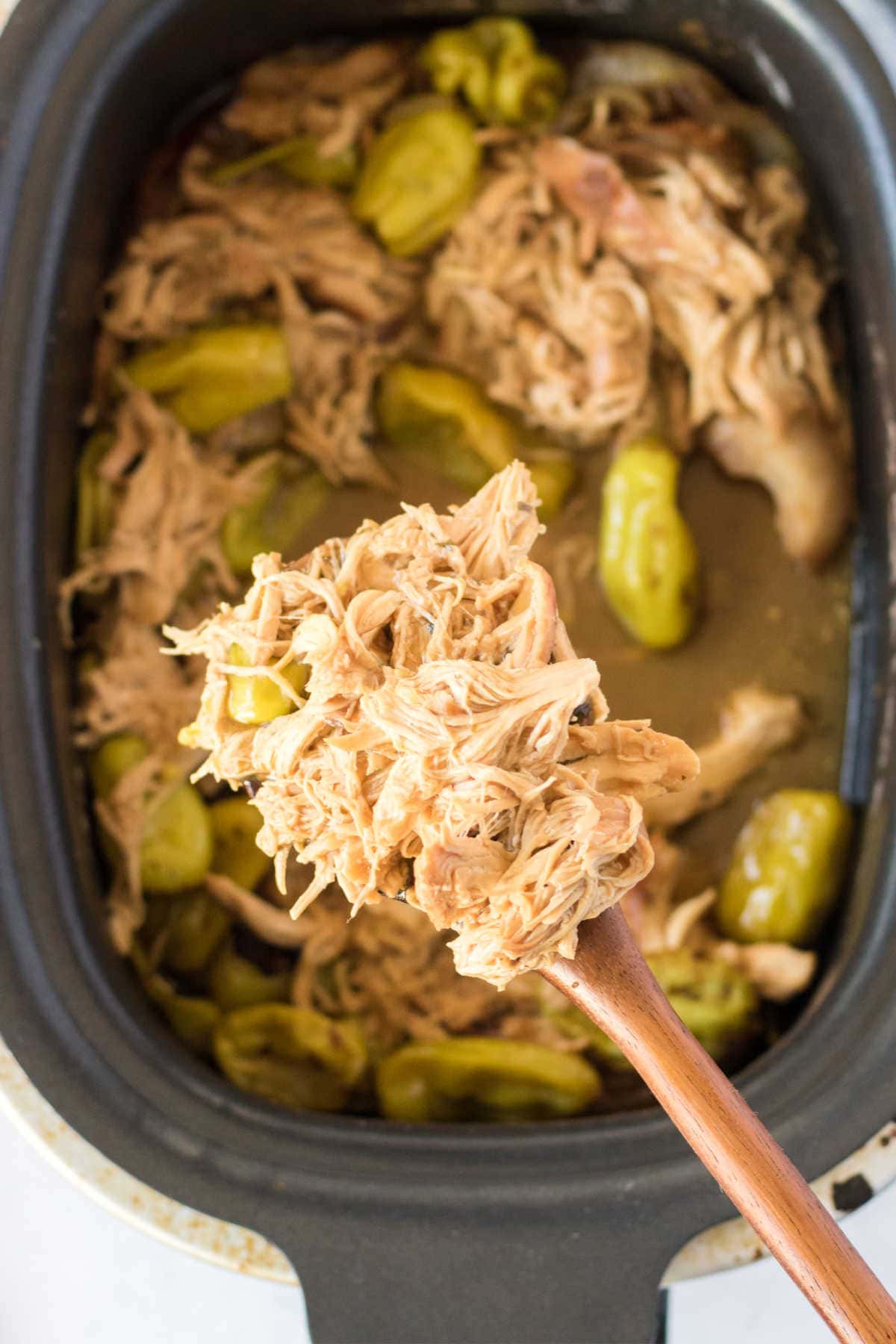 Spooning of Mississippi chicken over crockpot