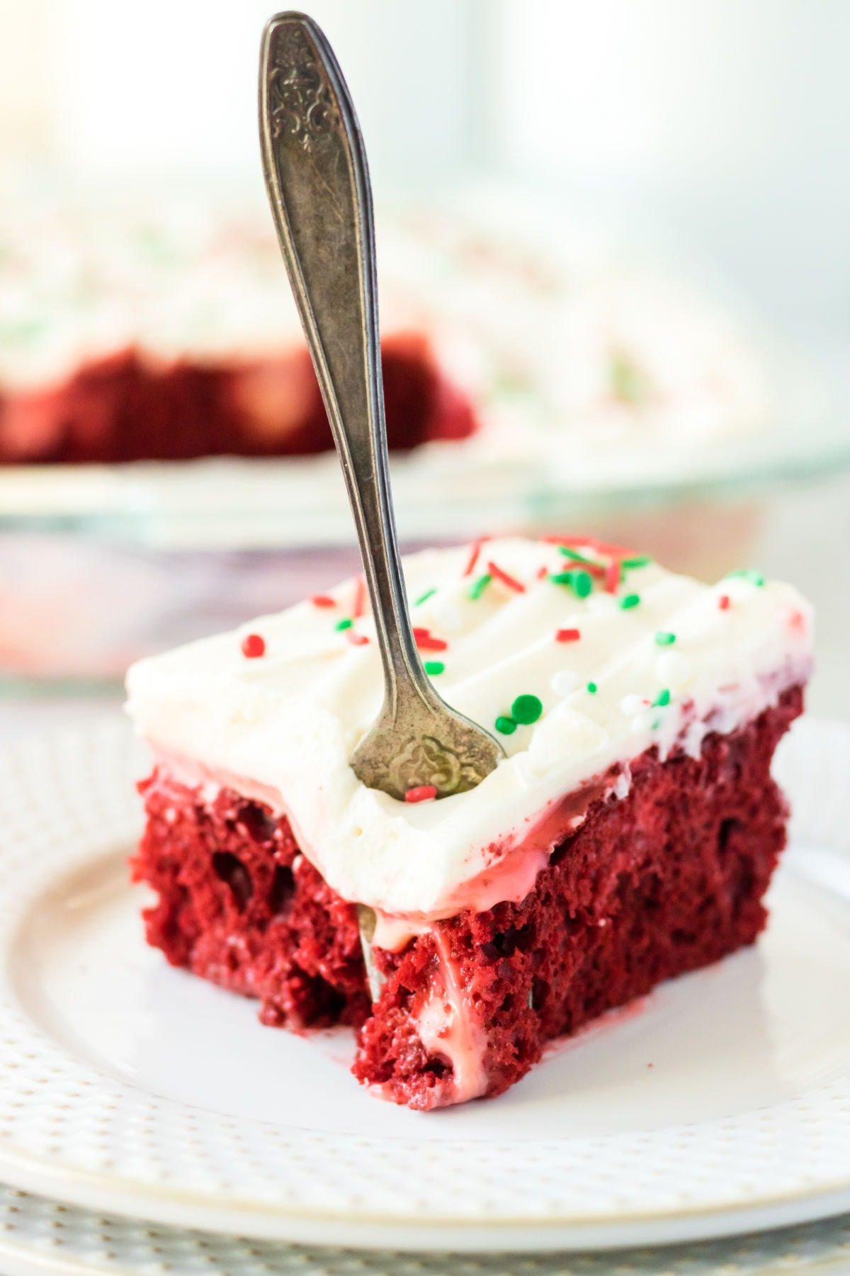 A piece of red velvet poke cake with a fork in it.