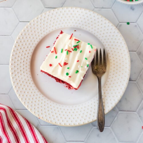 A piece of red velvet poke cake with a fork next to it.