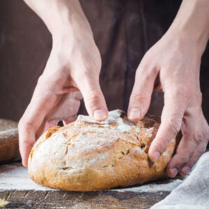 Closeup of hands holding a loaf of bread.