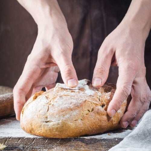 Closeup of hands holding a loaf of bread.
