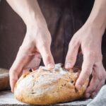 Hands holding a loaf of homemade bread with text overlay for Pinterest.