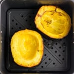 Close up of cooked halves of squash in an air fryer.