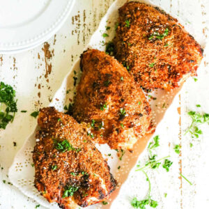 Overhead view of crispy chicken breasts on a white platter.