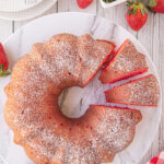 A marble plate displays a strawberry bundt cake with 2 slices cut to show the red cake color.