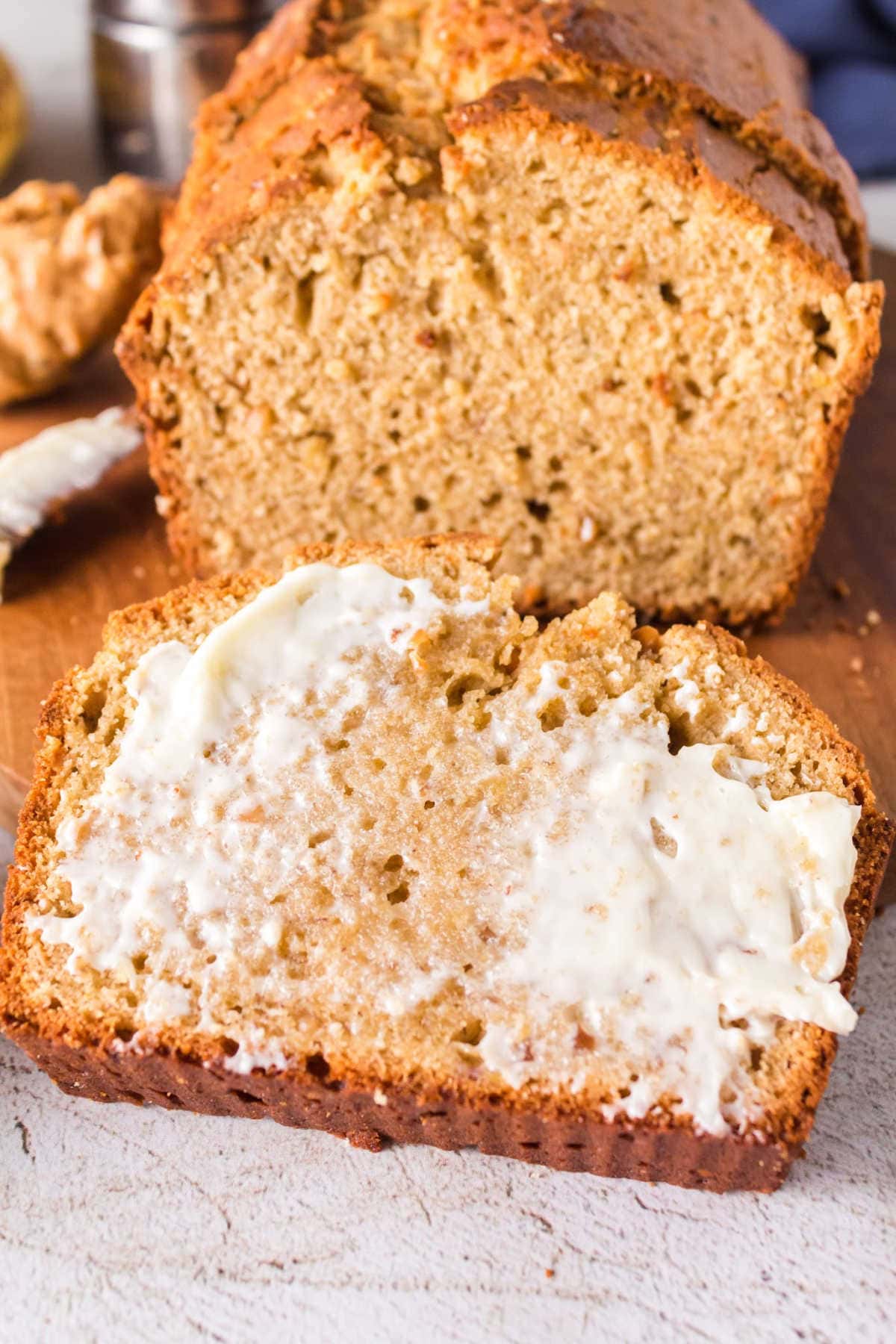 A slice of peanut butter banana bread is spread with butter.