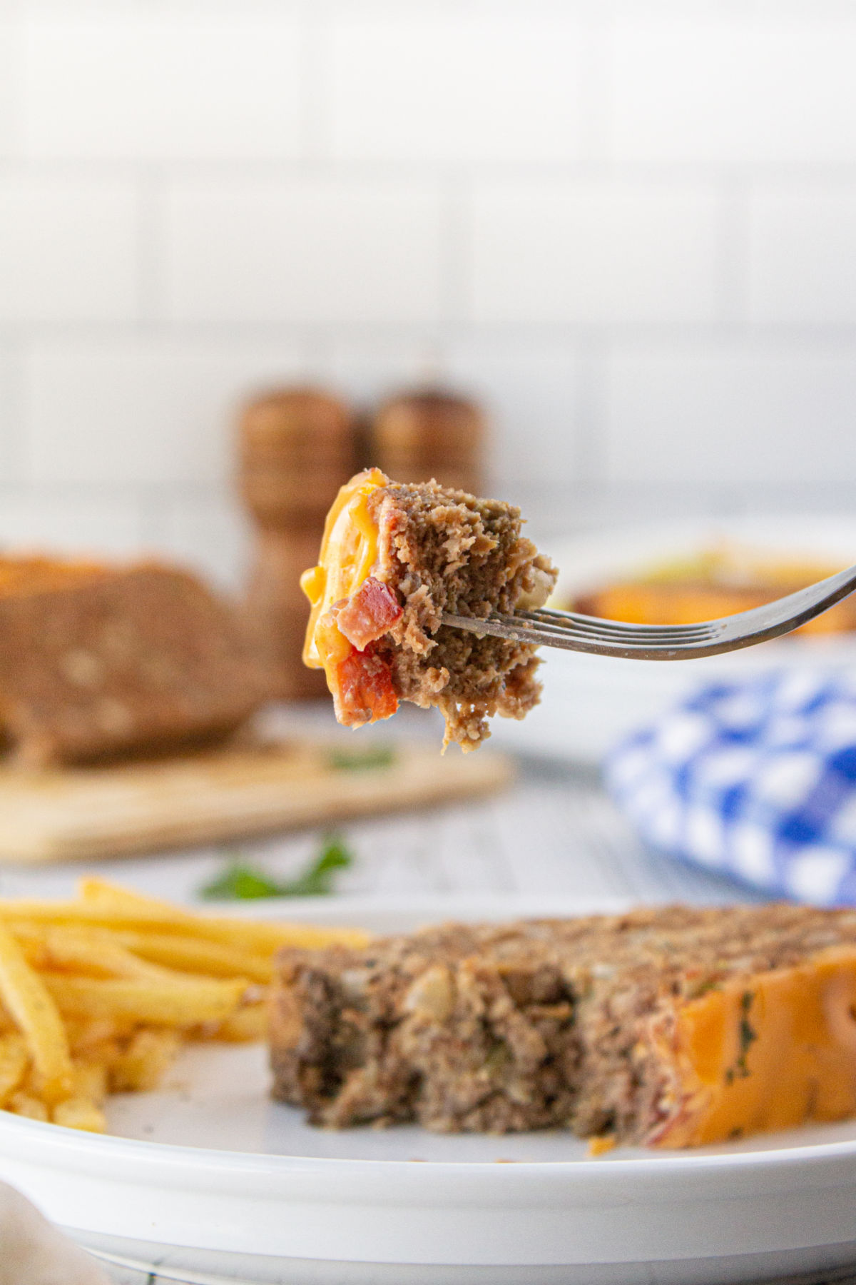 A forkful of meatloaf being picked up from the plate.