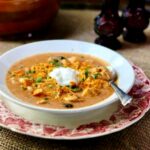 A bowl of enchilada soup on the table.