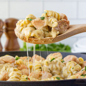 A spoonfool of mac and cheese being removed from the skillet.