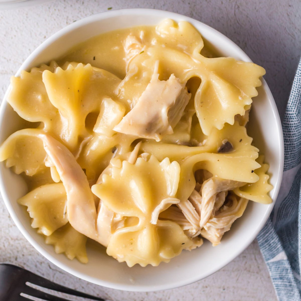 Overhead view of chicken and pasta in a white bowl.